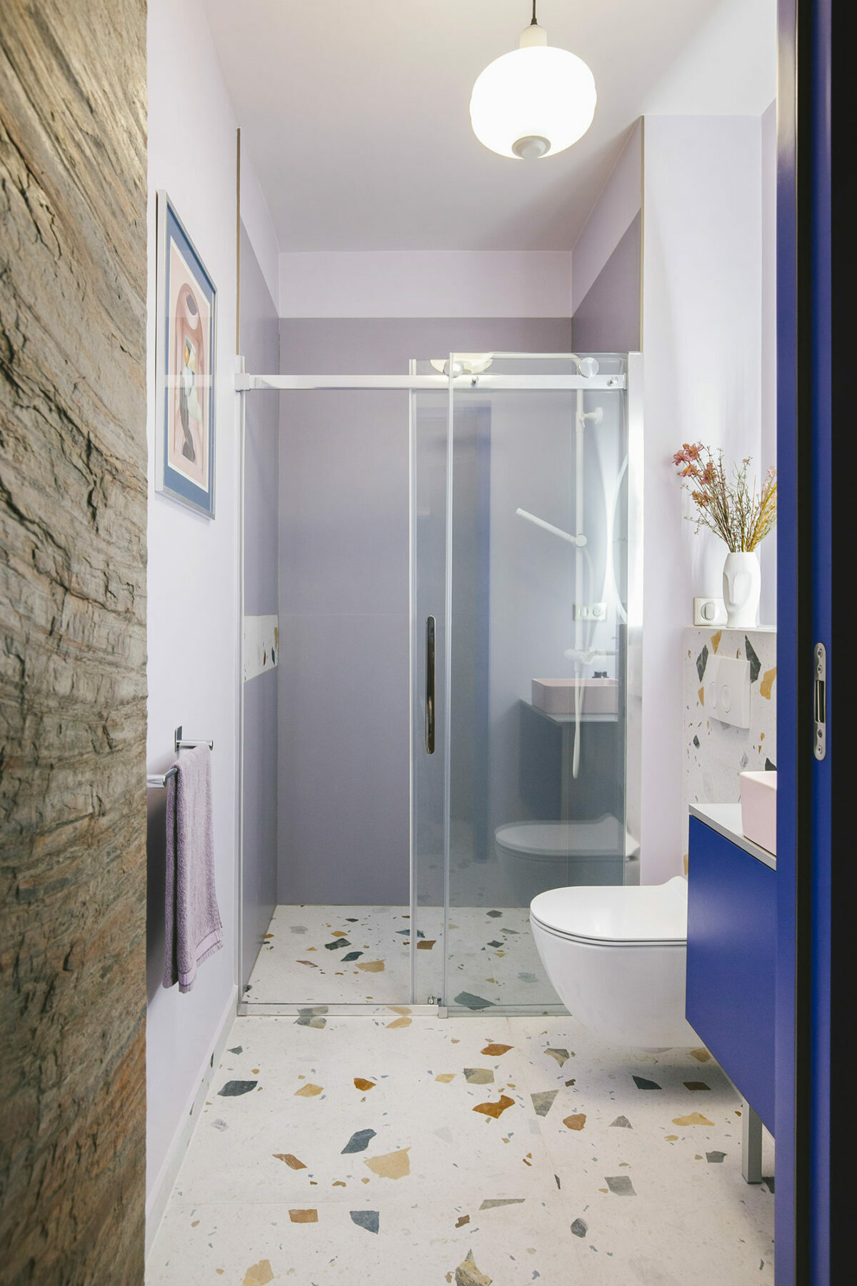 salle de douche italienne sol terrazzo grès cérame vase visage fleur séchée porte coulissante mur