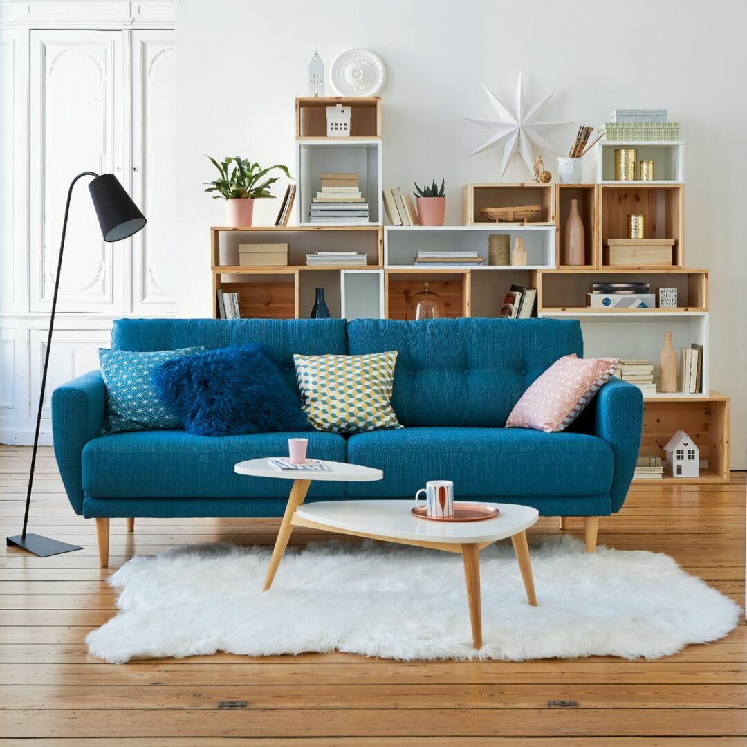 salon scandinave canapé bleu canard pieds en bois moulures aux murs tapis en fourrure blanche