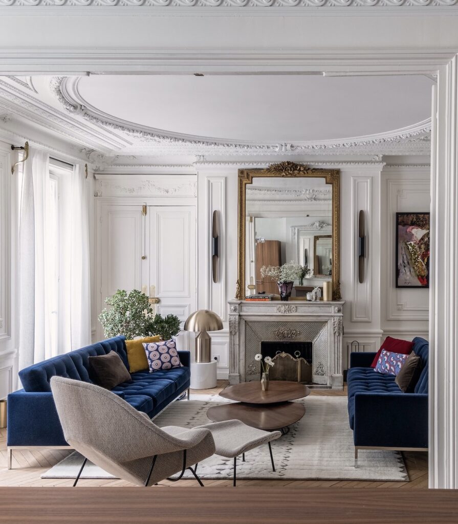 salon style paris canapé velours bleu cheminée marbre blanc miroir époque doré