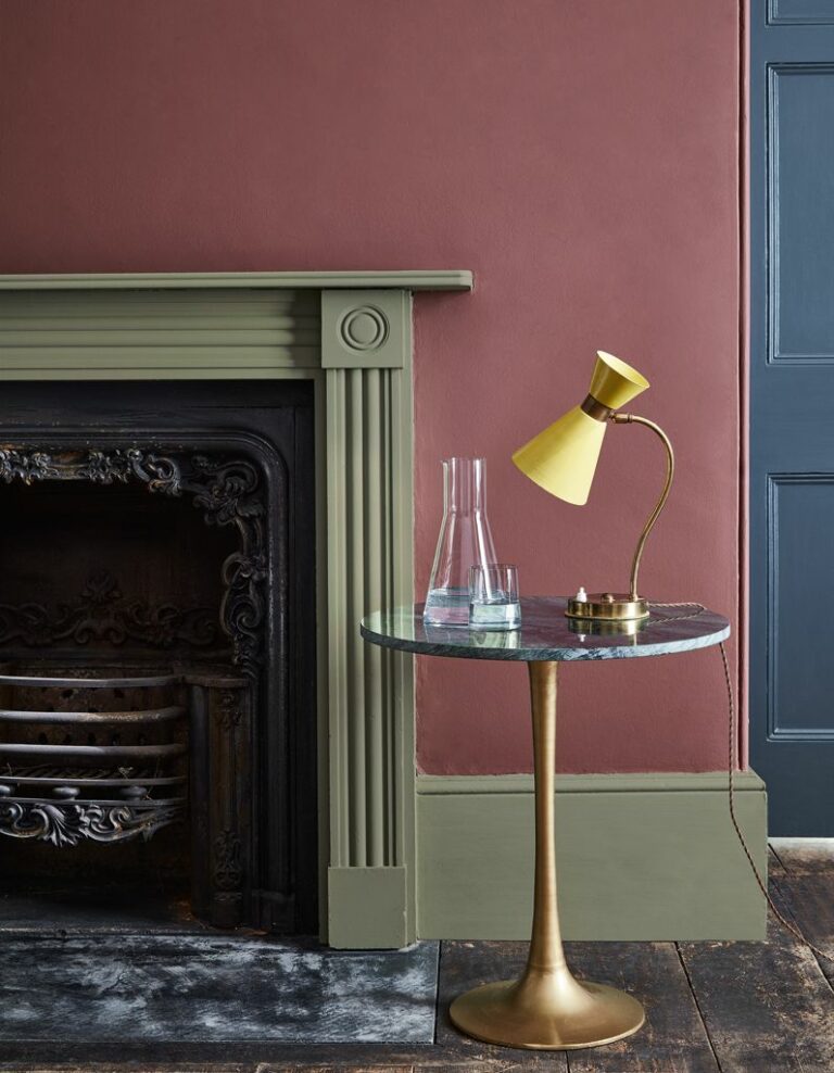 salon rustique cheminée vert kaki mur terracotta table basse ronde laiton marbre noir