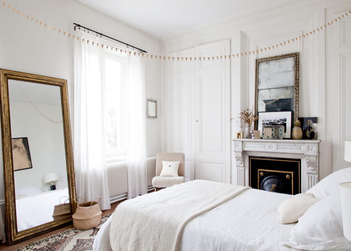 chambre avec cheminée blanc guirlande miroir rectangle moulure dorure tapis ethnique