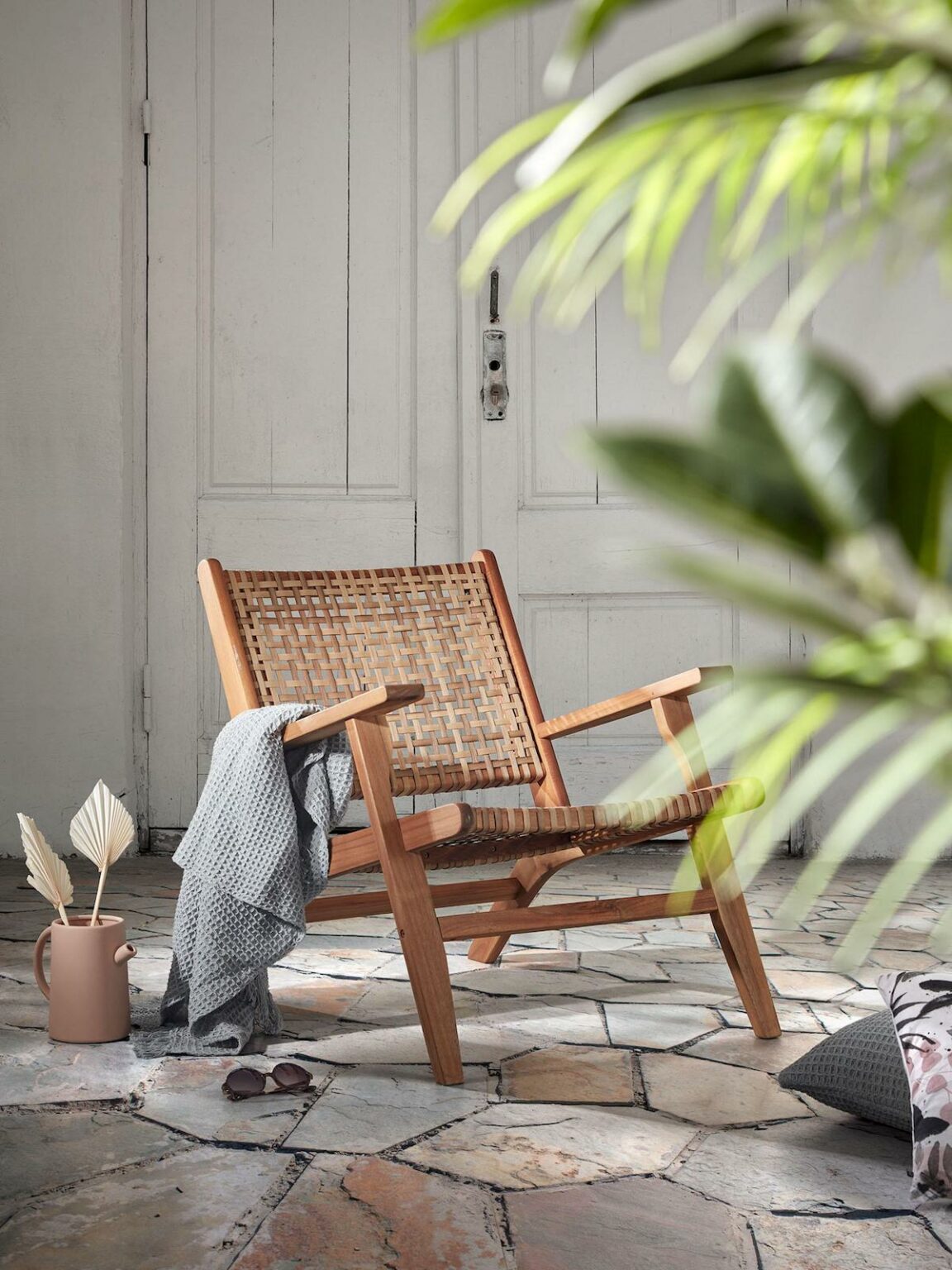 fauteuil cannage bois plante verte plaid gris coussin de sol