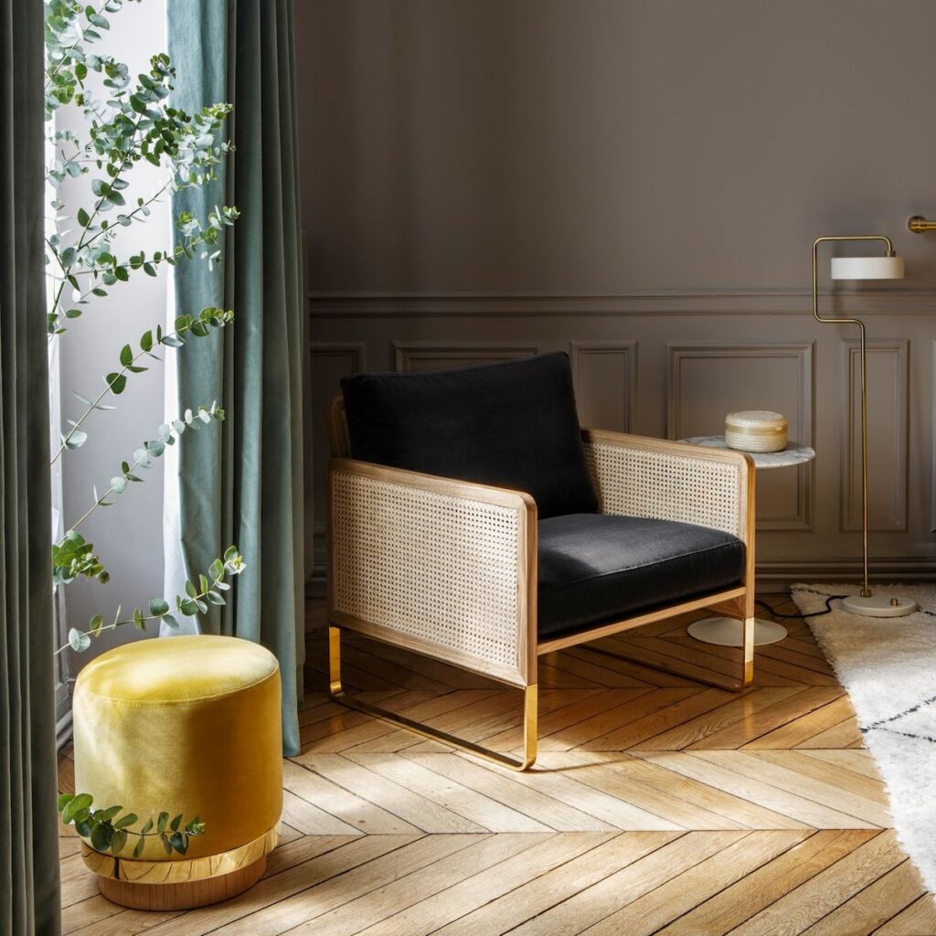 salon élégant parquet chevron bois pouf jaune velours laiton fauteuil noir cannage