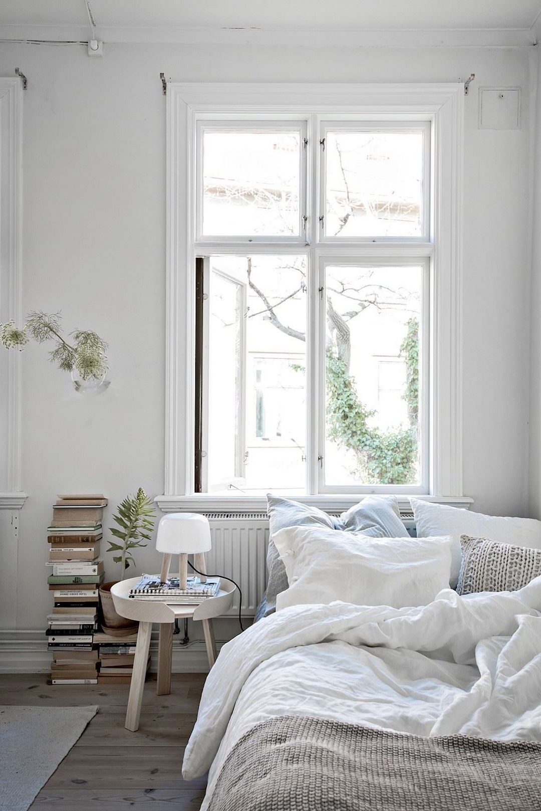 chambre minimaliste lit double blanc parquet bois tabouret ronde