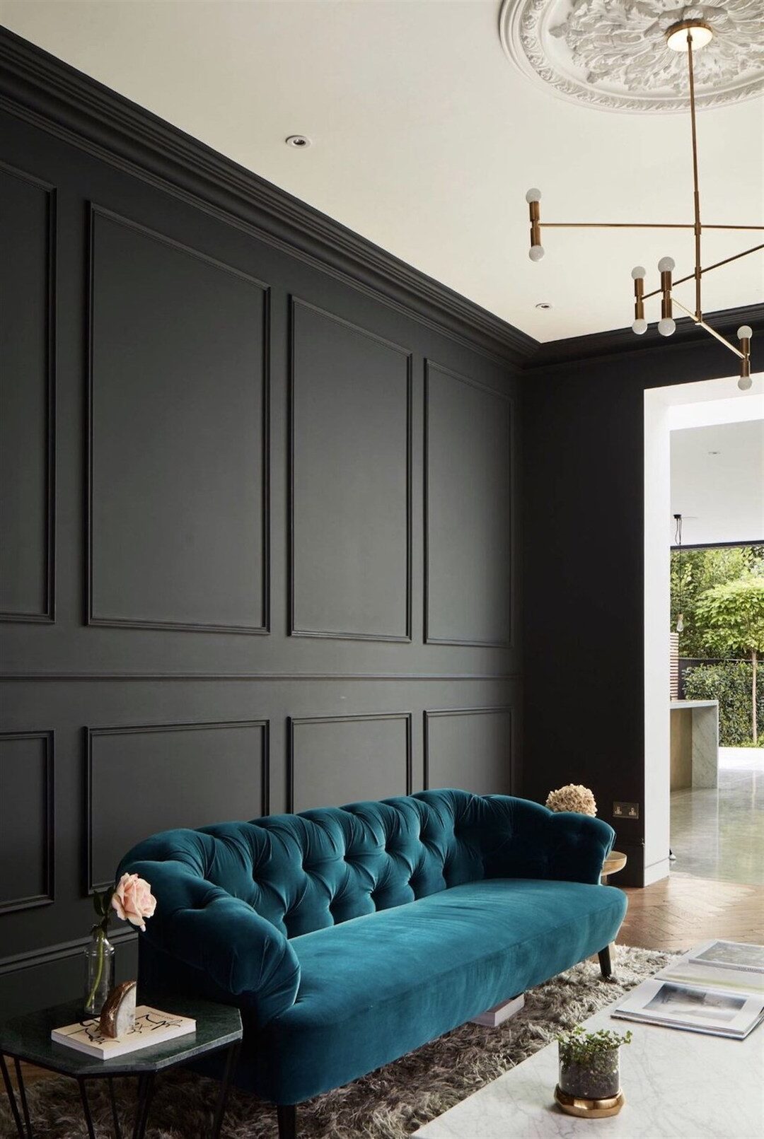 salon élégant canapé droit bleu velours mur moulure noir suspension laiton