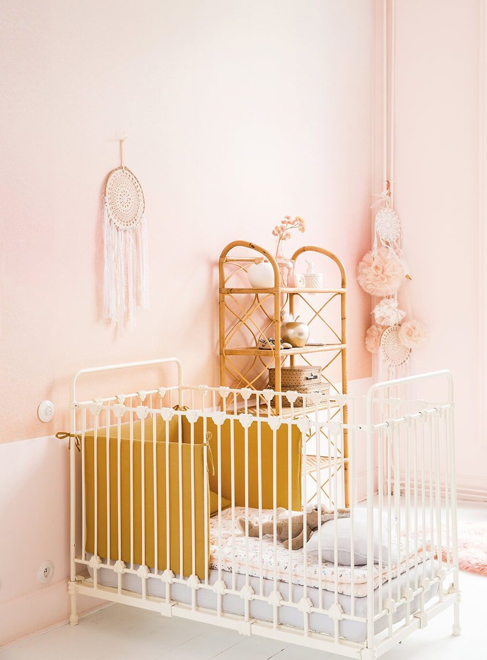 chambre enfant mur rose pastel berceau barreaux blancs plaid jaune moutarde meuble rotin deco murale