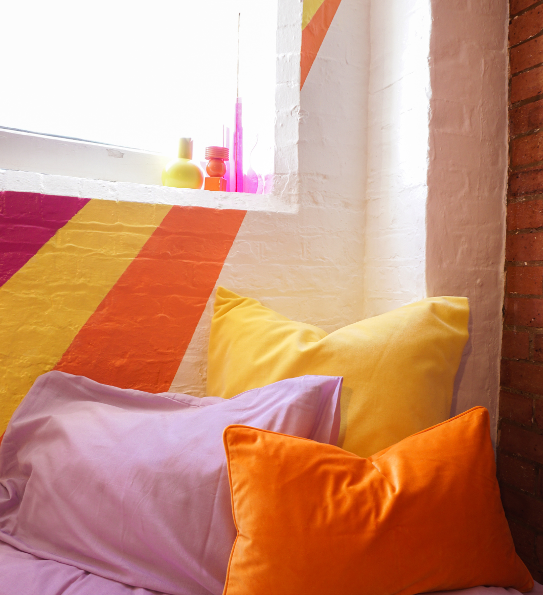 chambre d'amis mur brique blanc rouge coussin jaune orange violet