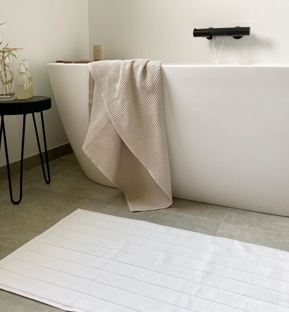 baignoire blanc arrondie tapis blanc tabouret fer noir