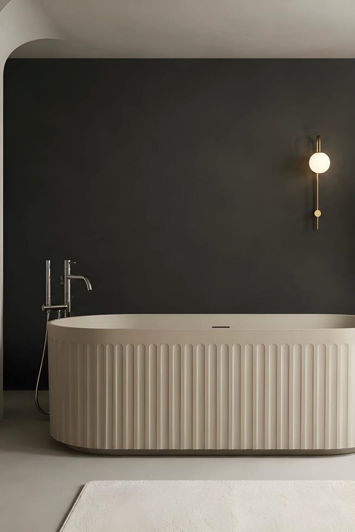 baignoire îlot cannelée beige devant un mur foncé avec applique ronde et robinetterie sur pied