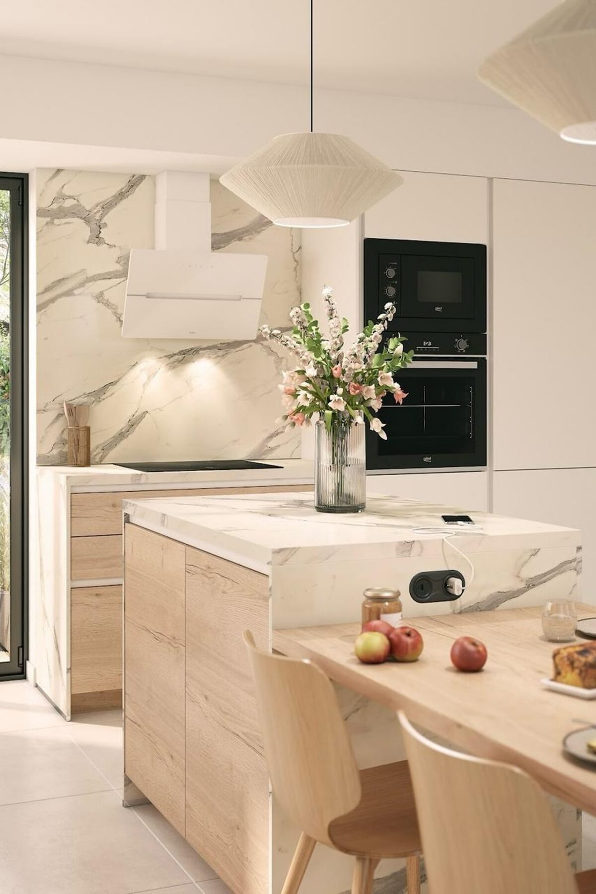 Première cuisine équipée lumineuse avec façades en bois clair, plan de travail effet marbre, îlot central et électroménager noir encastré