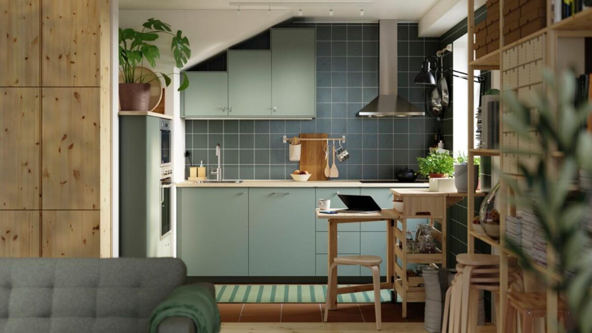 Cuisine ouverte vert sauge avec plan de travail clair, crédence vert-gris et rangements en bois clair