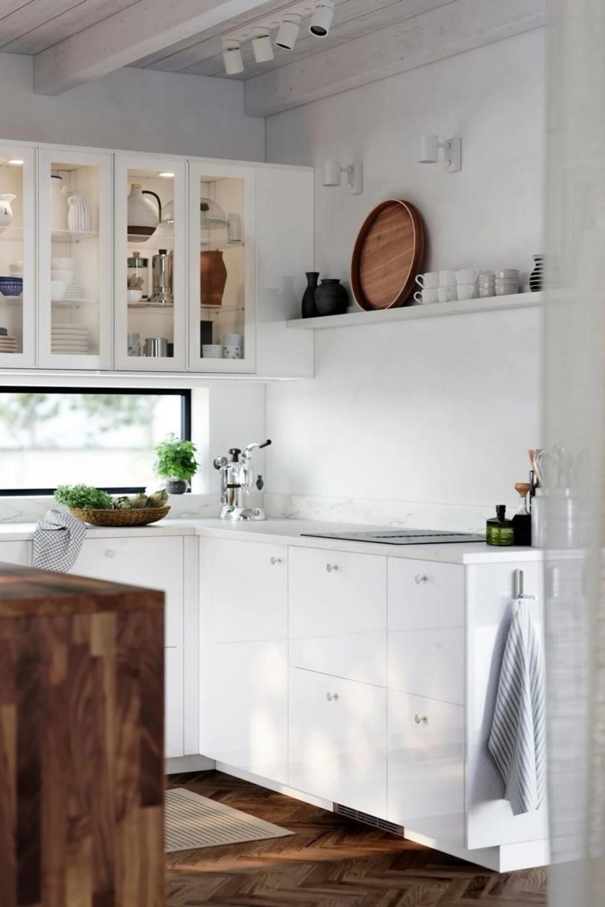 Cuisine blanche lumineuse avec plan de travail clair, évier sous fenêtre et îlot en bois