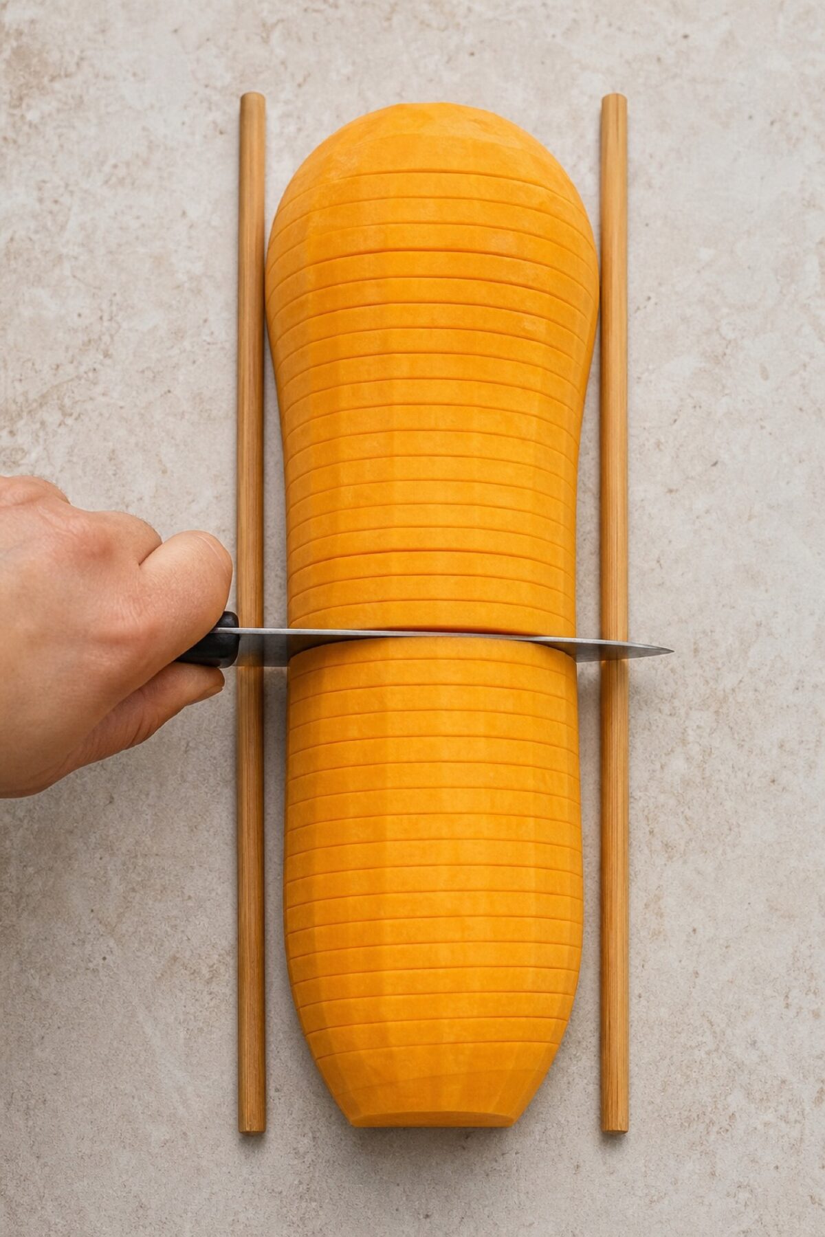 demi-butternut découpée en entailles transversales parallèles avec deux baguettes en bois utilisées comme butées