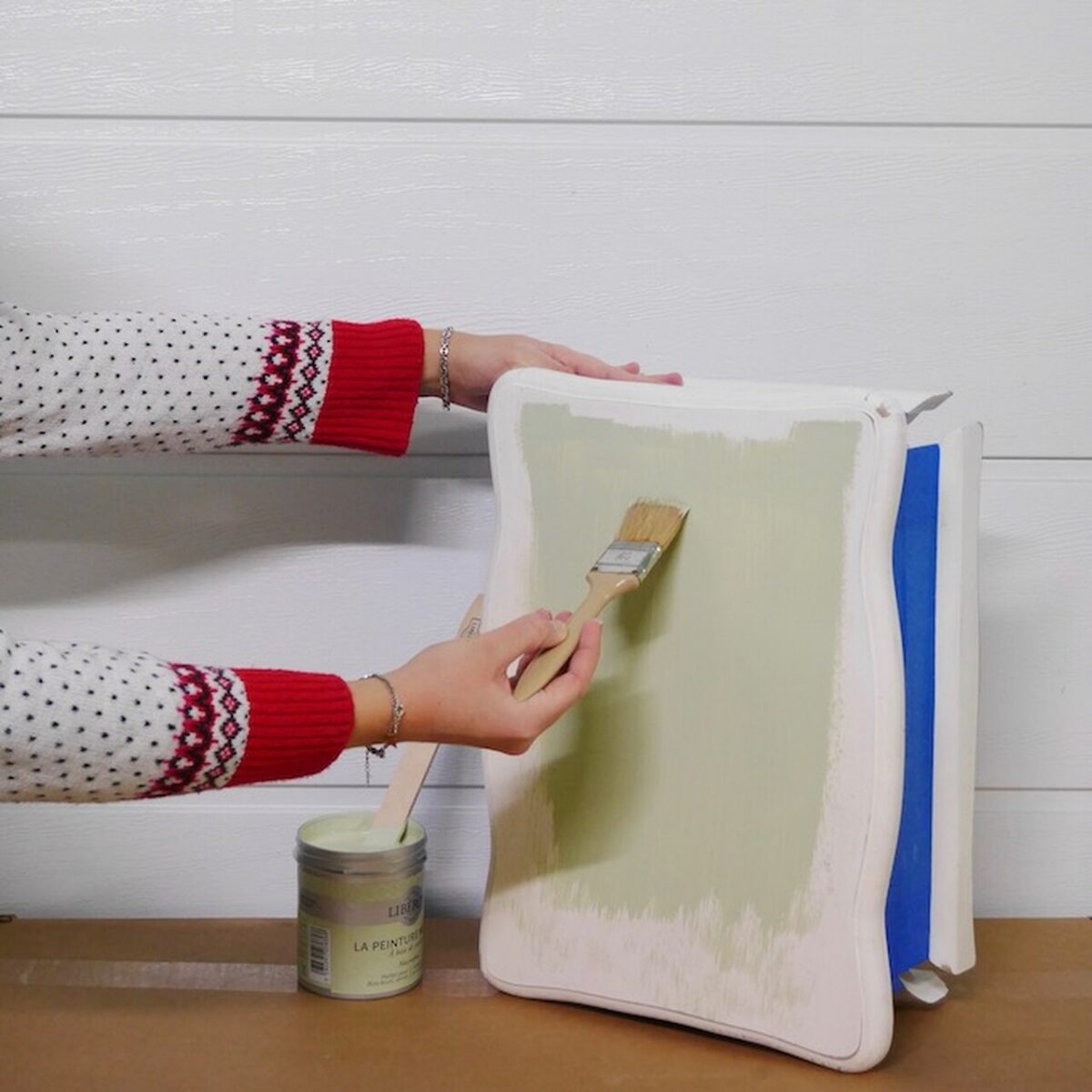 Application au pinceau d’une peinture vert clair sur le côté de la table de chevet