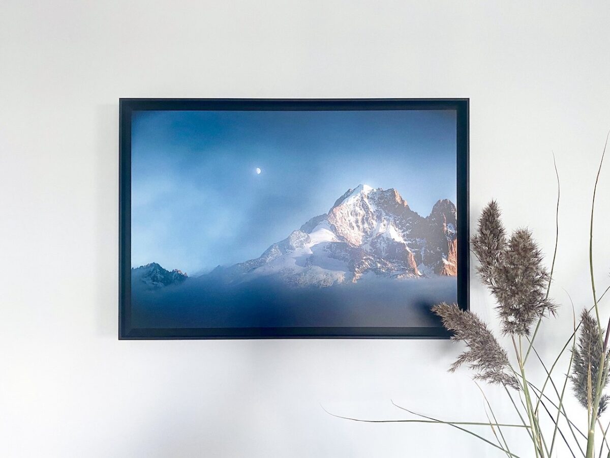 Photographie encadrée de l’Aiguille Verte éclairée par le soleil couchant, avec la lune dans un ciel bleu-gris