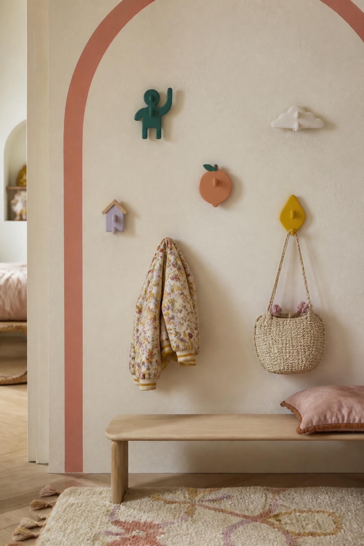 Patères enfant colorées en forme de nuage, de fruit, de maison et de silhouette ludique sur un mur crème