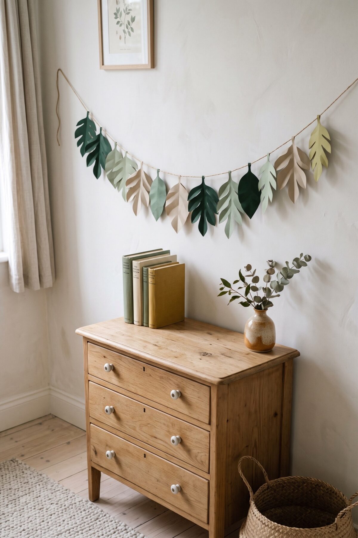 Guirlande de feuilles en papier au-dessus d’une commode en bois dans une chambre d’enfant