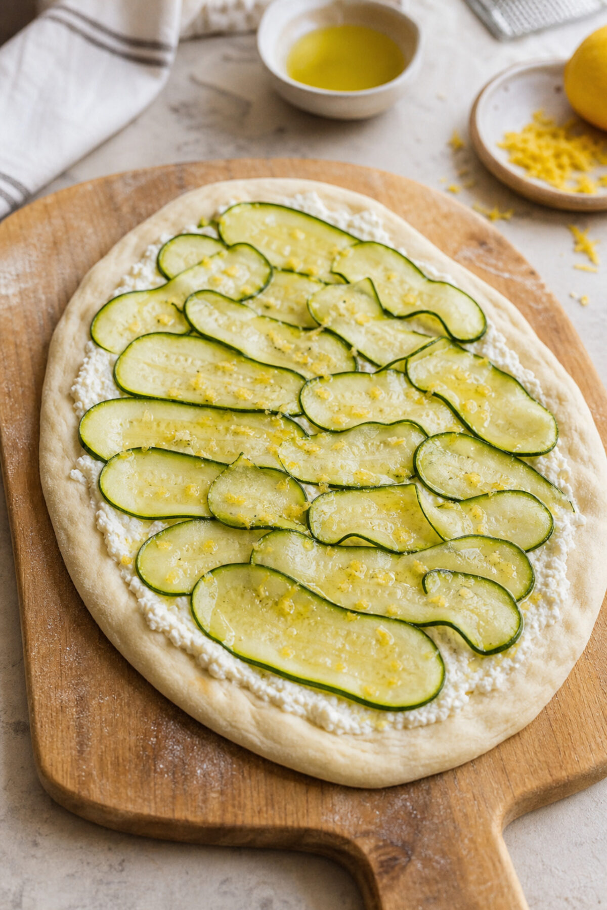 Pâte à pizza garnie de ricotta, mozzarella et rubans de courgette avant cuisson