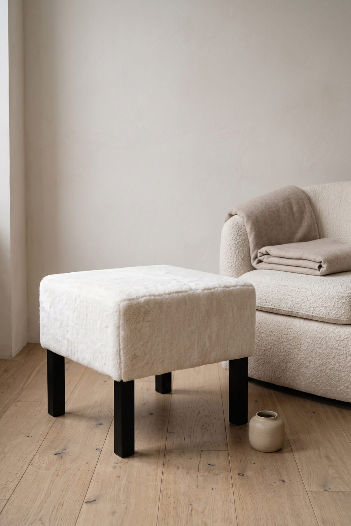 Pouf LACK IKEA recouvert de fausse fourrure écrue dans un intérieur cosy
