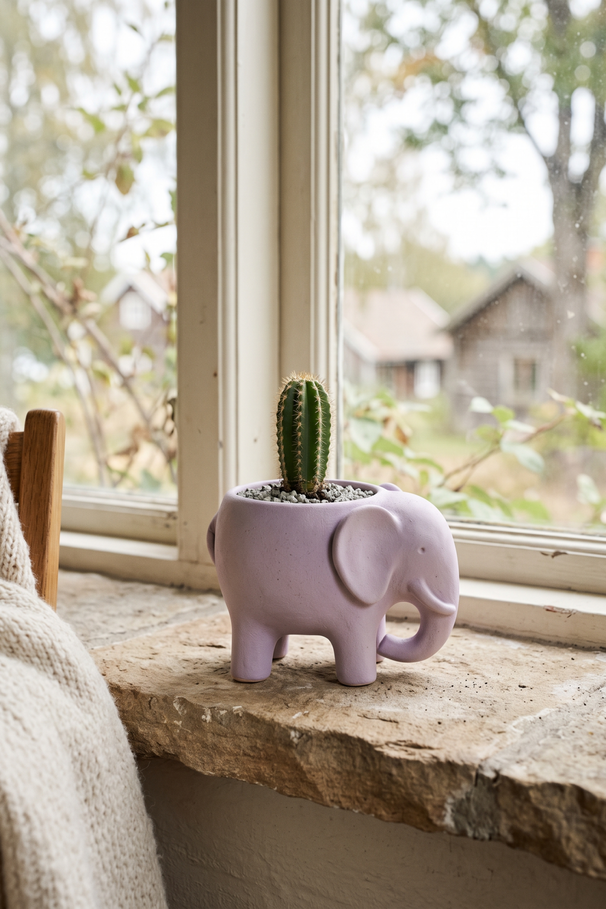 Petit pot éléphant pastel avec cactus sur un rebord de fenêtre