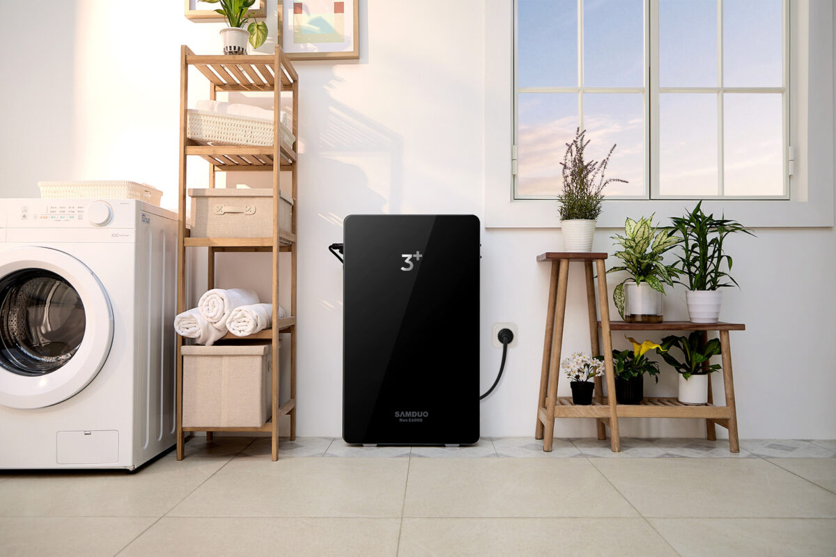 Batterie SAMDUO NEX E6000 noire contre un mur blanc à côté d’un lave-linge et d’étagères en bois