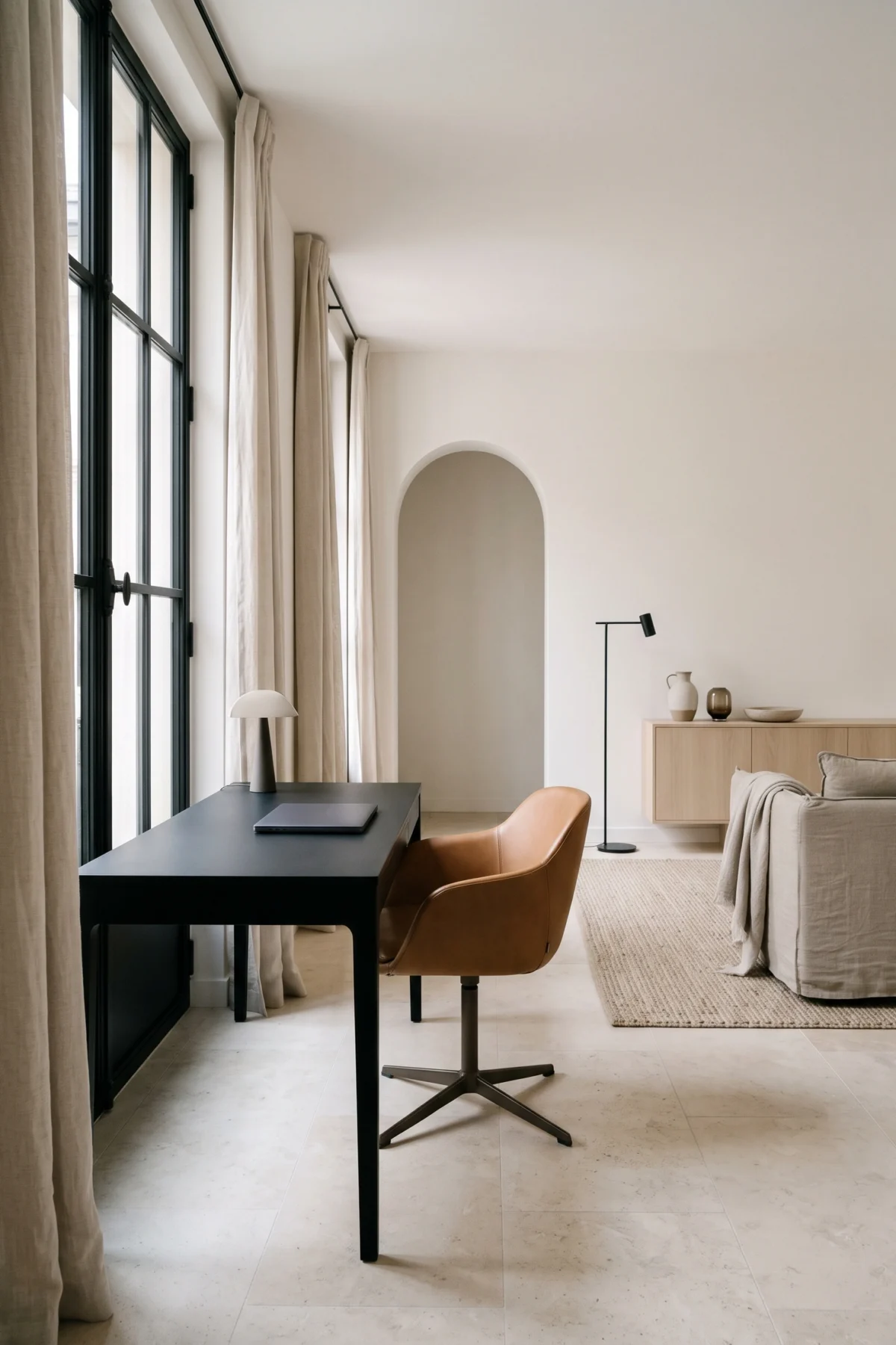 Bureau noir près d’une fenêtre à cadre noir dans un salon aux matières naturelles