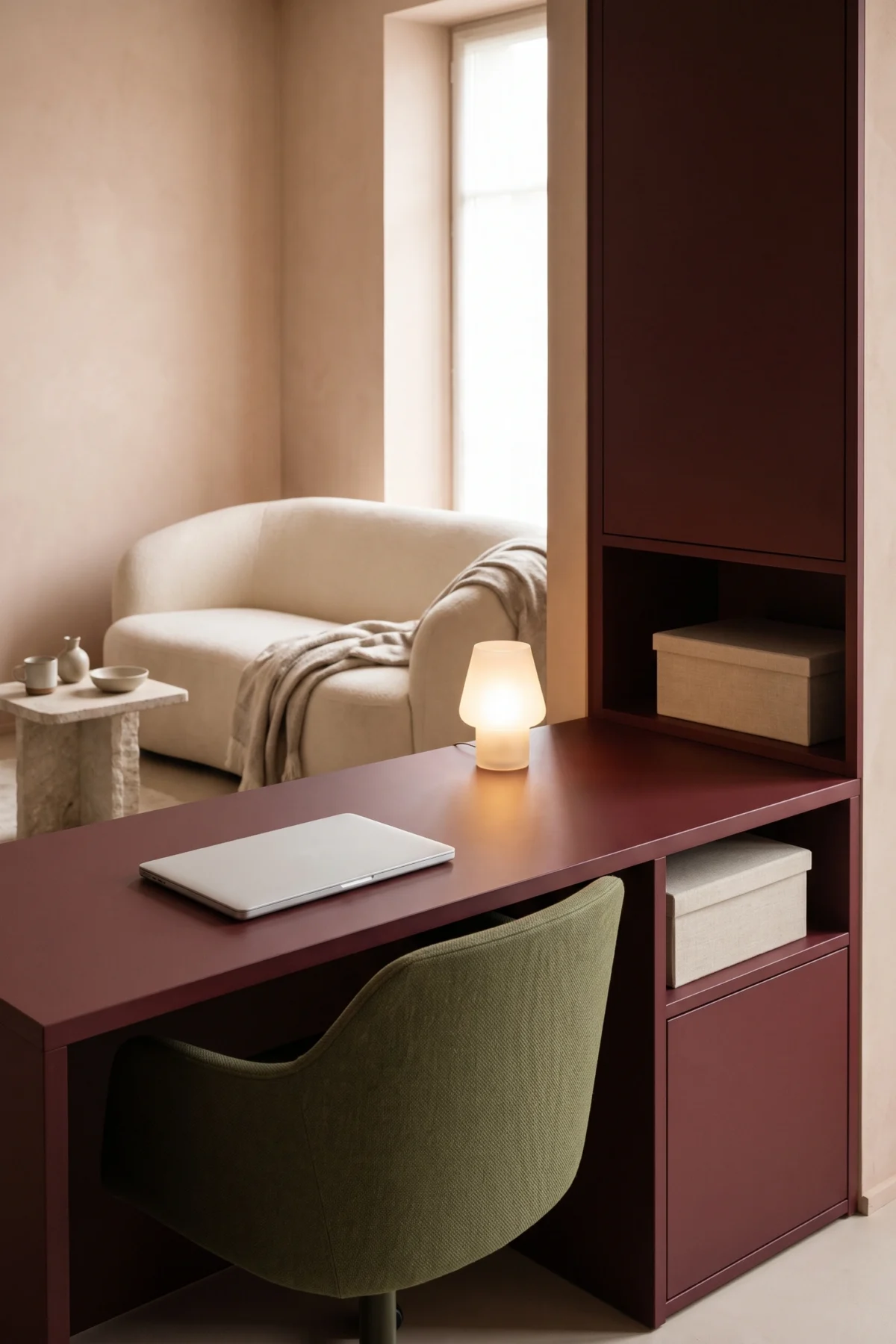 Coin bureau rangé avec ordinateur fermé et lampe allumée dans un salon terracotta