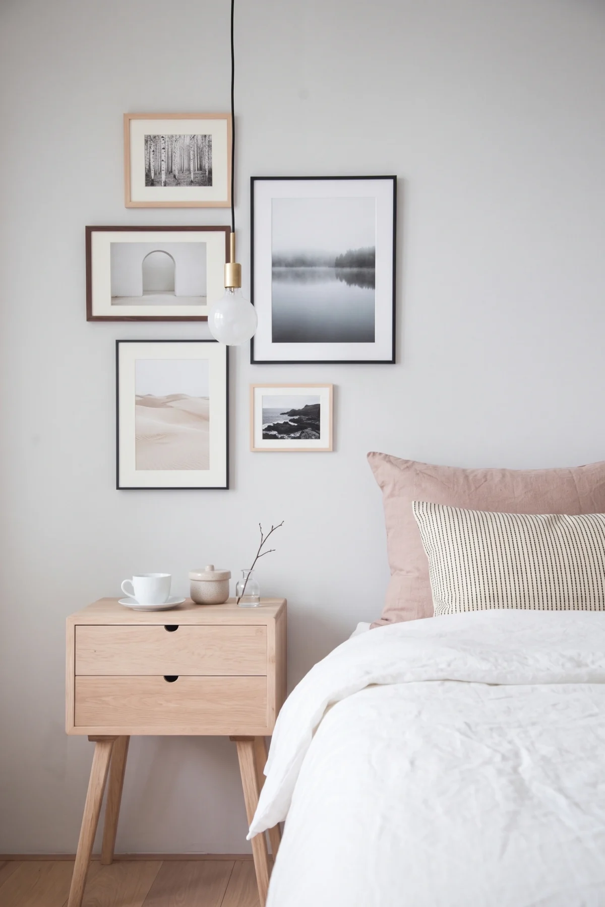 Galerie de photographies encadrées près d’un lit blanc et rose poudré