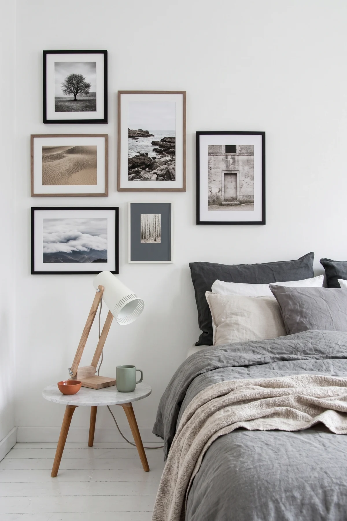 Mur de photographies encadrées dans une chambre aux textiles gris et lin naturel
